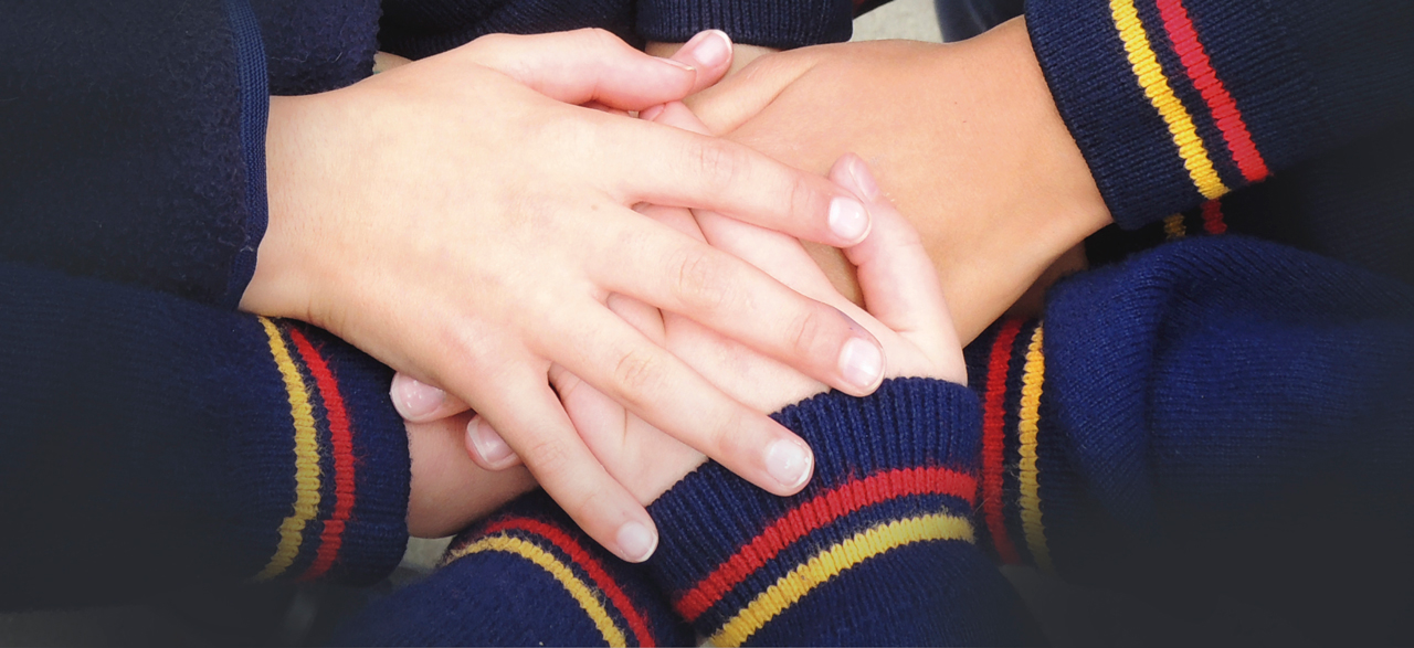 manos encimadas de alumnos